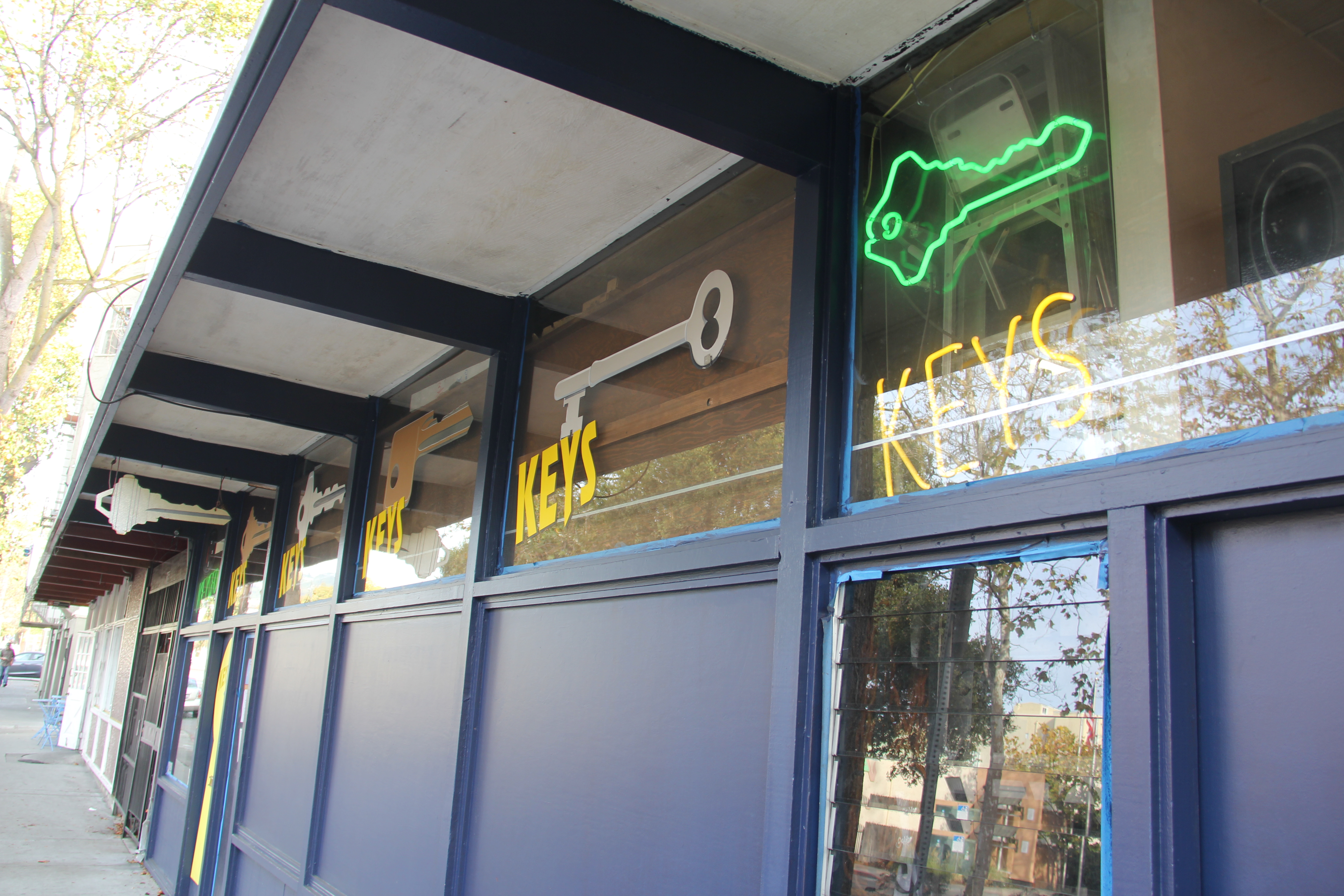 Photo of neon KEYS sign hanging in window of lock and key shop